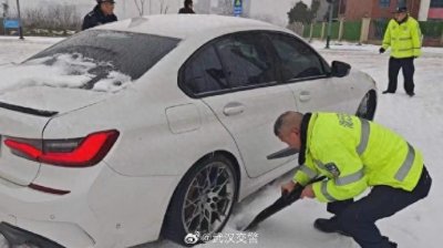​轿车因积雪打滑，武汉交警拿出防爆盾牌铲雪